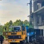 Borehole drilling rig set up beside an apartment block under construction in Kenya