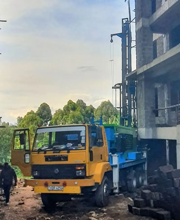 Borehole drilling rig set up beside an apartment block under construction in Kenya